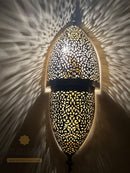 Decorative wall light with intricate patterns on a textured wall.