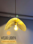 Yellow pendant light with a bulb inside, branded as Atlas Lights, against a neutral background.