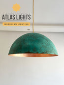 Green pendant light with gold interior on a white wall, branded as Atlas Lights.