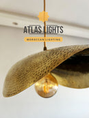Gold pendant light with textured shade on a white background, featuring 'Atlas Lights' branding.