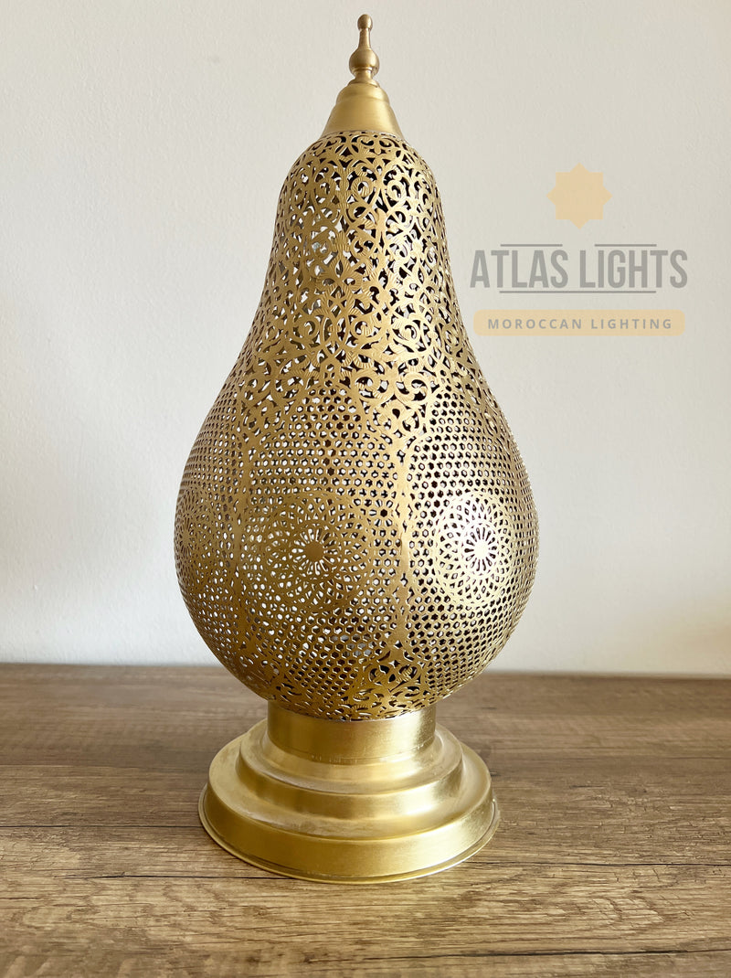 Decorative gold lamp with intricate patterns on a wooden surface, branded 'Atlas Lights'.