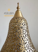 Decorative gold lampshade with intricate patterns on a plain background, branded 'Atlas Lights'.