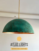 Green pendant light with gold interior on a white wall, featuring Atlas Lights branding.